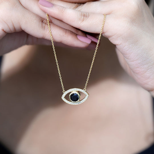 Close-up evil eye pendant necklace with dark center stone and white pavé rim