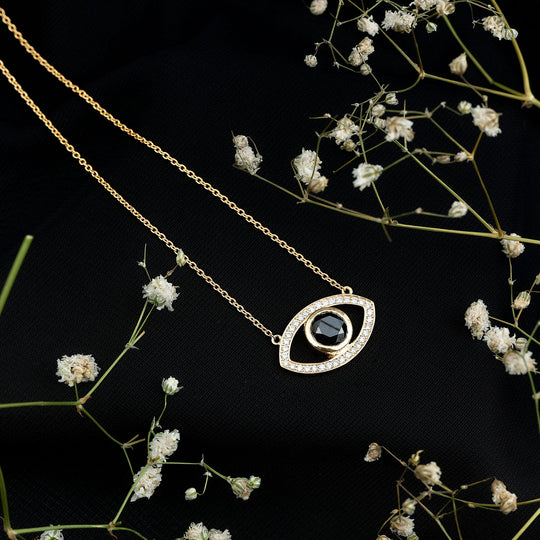 Gold-toned evil eye pendant necklace with dark center stone and outlined white pavé