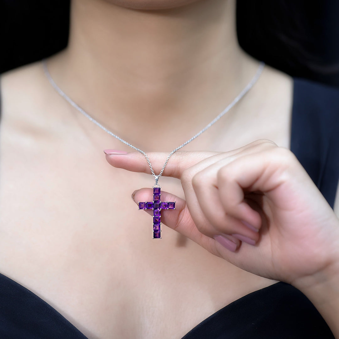 Close-up amethyst cross pendant with purple princess-cut stones on silver chain