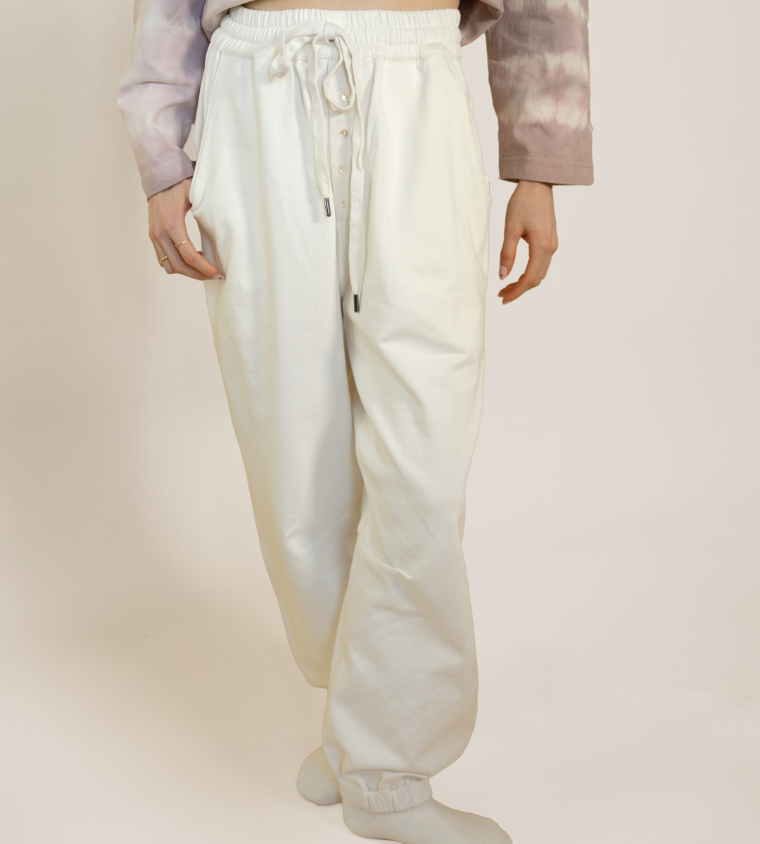 Off-white lounge pants with elastic waistband, drawcord ties, and side pockets