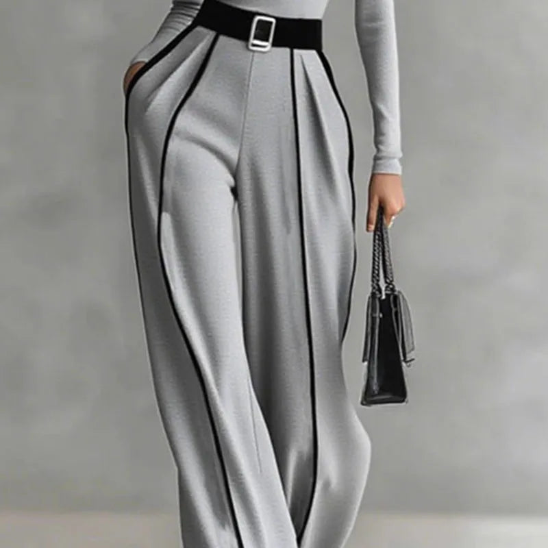 Gray wide-leg trousers with pleated panel lines and black belt; mock-neck top