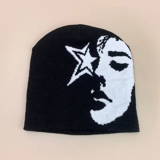 Black beanie with moon and star graphic, white face print, ribbed knit cuff