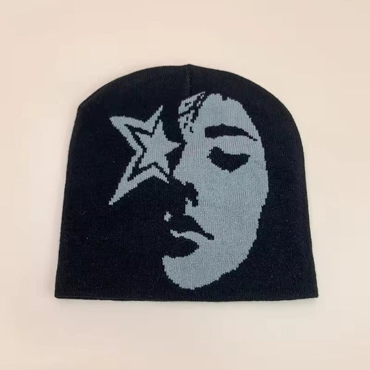 Black beanie with moon and star graphic, light gray face print, ribbed knit cuff