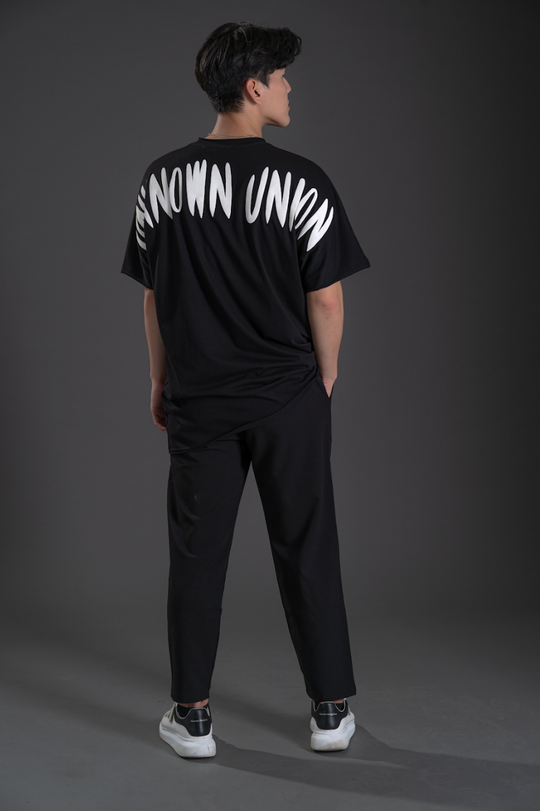 Black T-shirt back view with bold white “UNKNOWN” text graphic across shoulders.