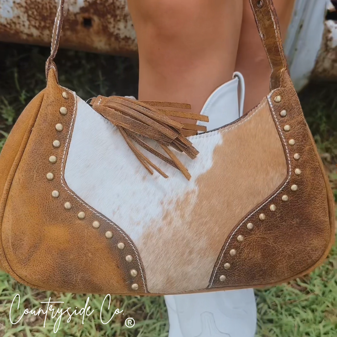 Front cowhide leather panel with tan-and-white coloring, fringe detail, and stud border