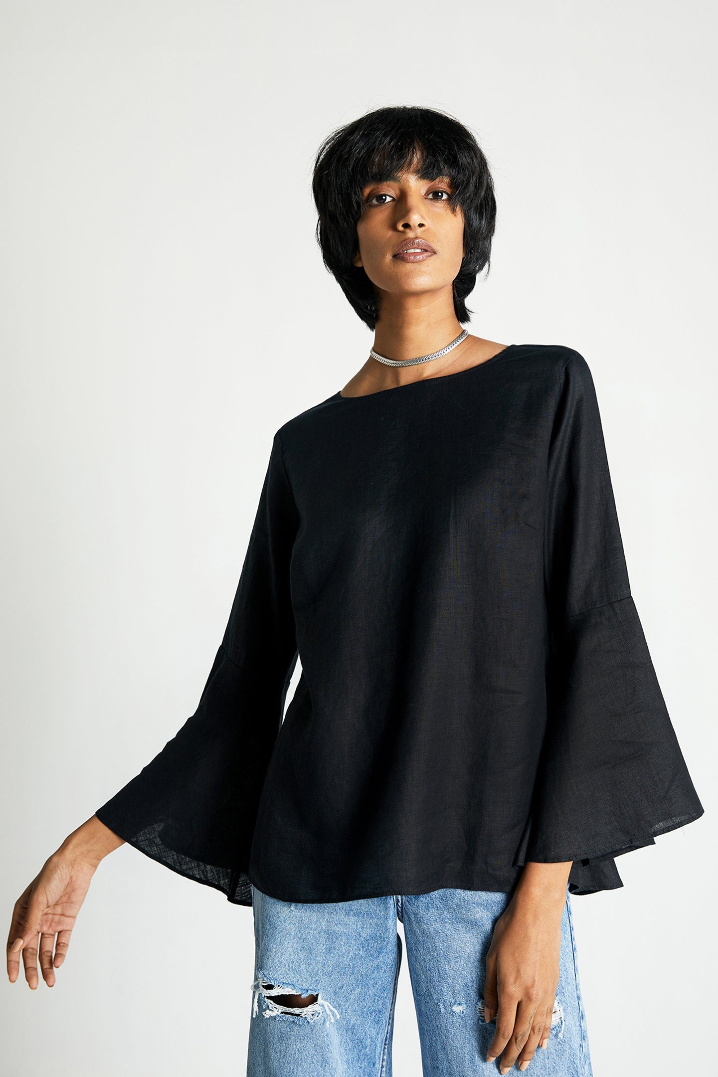 The Button Back Shirt, black dolman top with wide flare sleeves and curved hem.
