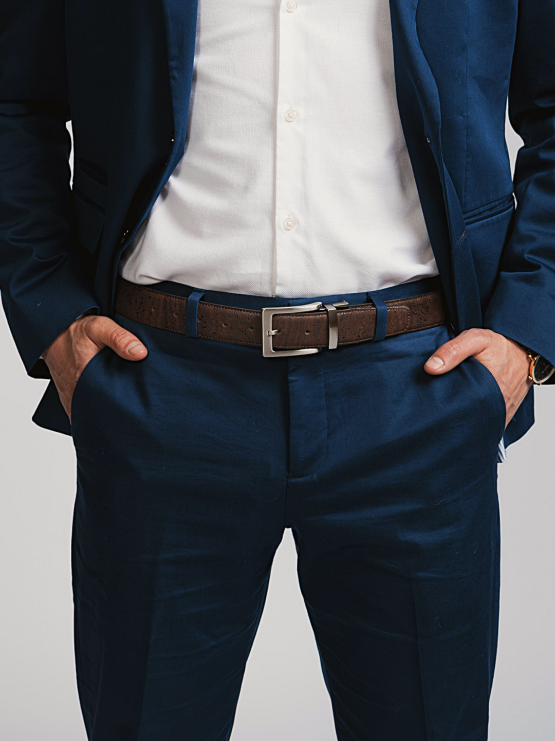 Brown/black reversible cork men’s belt with silver buckle, worn with navy pants
