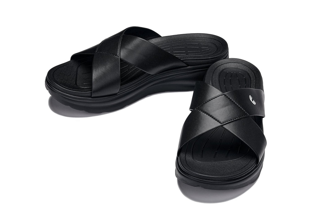 Black matte slide sandals with leather-look straps and stitched cross-strap detail.