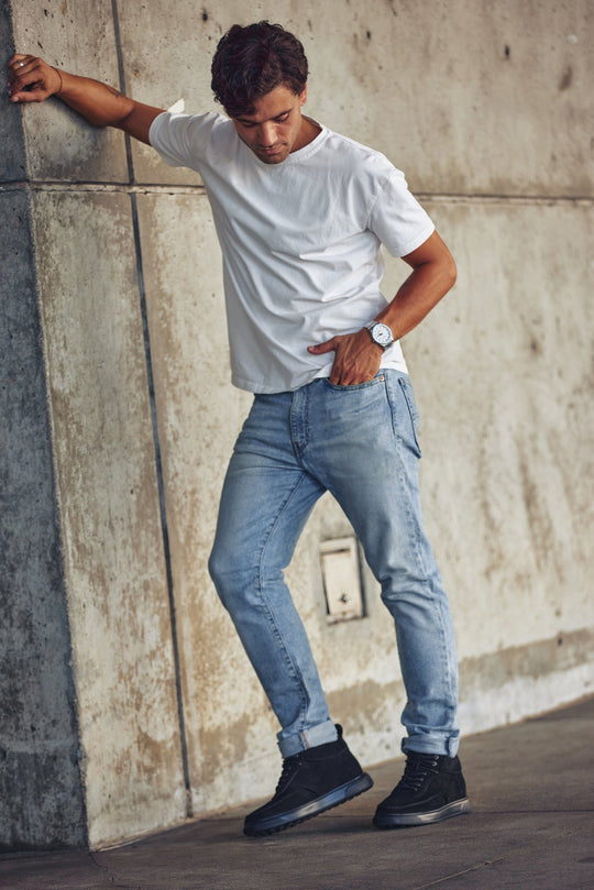 Black lace-up sneaker boots worn with jeans; moc-toe silhouette and sole