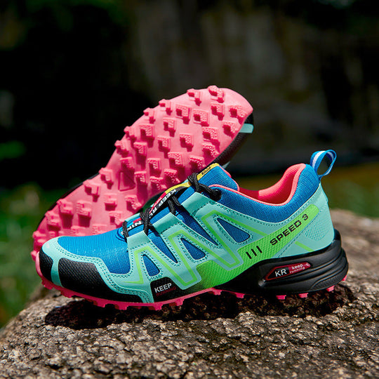 Off-road hiking shoe: turquoise upper, bright pink outsole with chunky traction.
