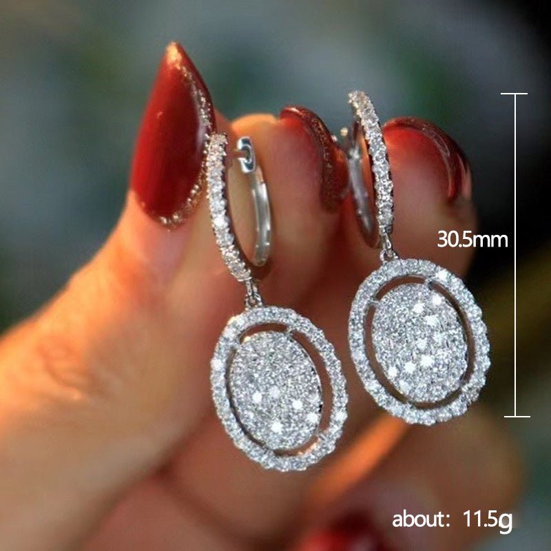 Oval drop earrings in white gold tone with pavé border around the oval center stones