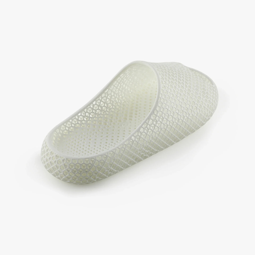 White 3D-printed slipper, side view with open toe and textured honeycomb pattern