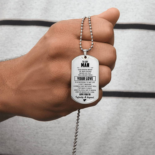 Silver dog tag necklace held in hand, engraved message on pendant