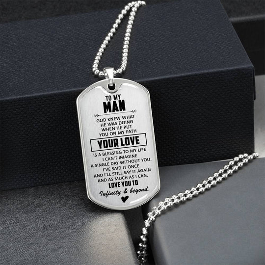 Silver dog tag necklace with engraved text and heart, on display