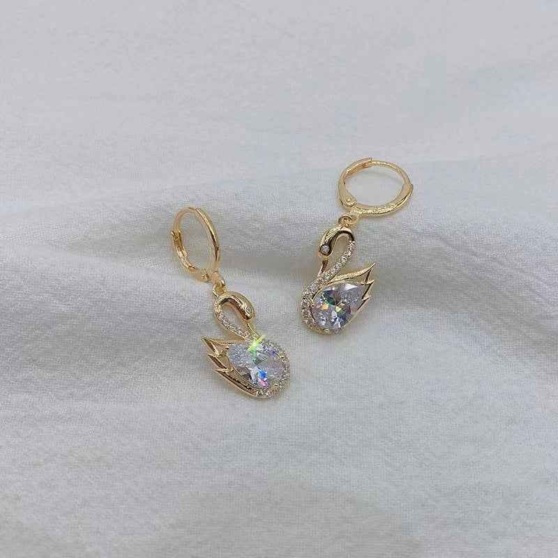 Gold-tone swan drop earrings with clear faceted teardrop stones and rhinestone trim.