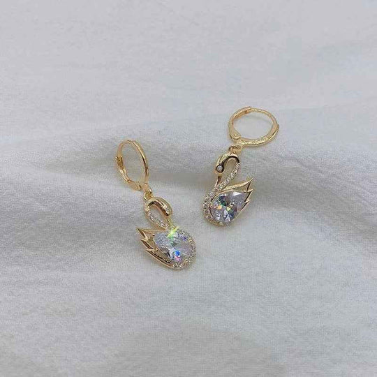 Gold-tone swan drop earrings with clear faceted teardrop stones and rhinestone trim.
