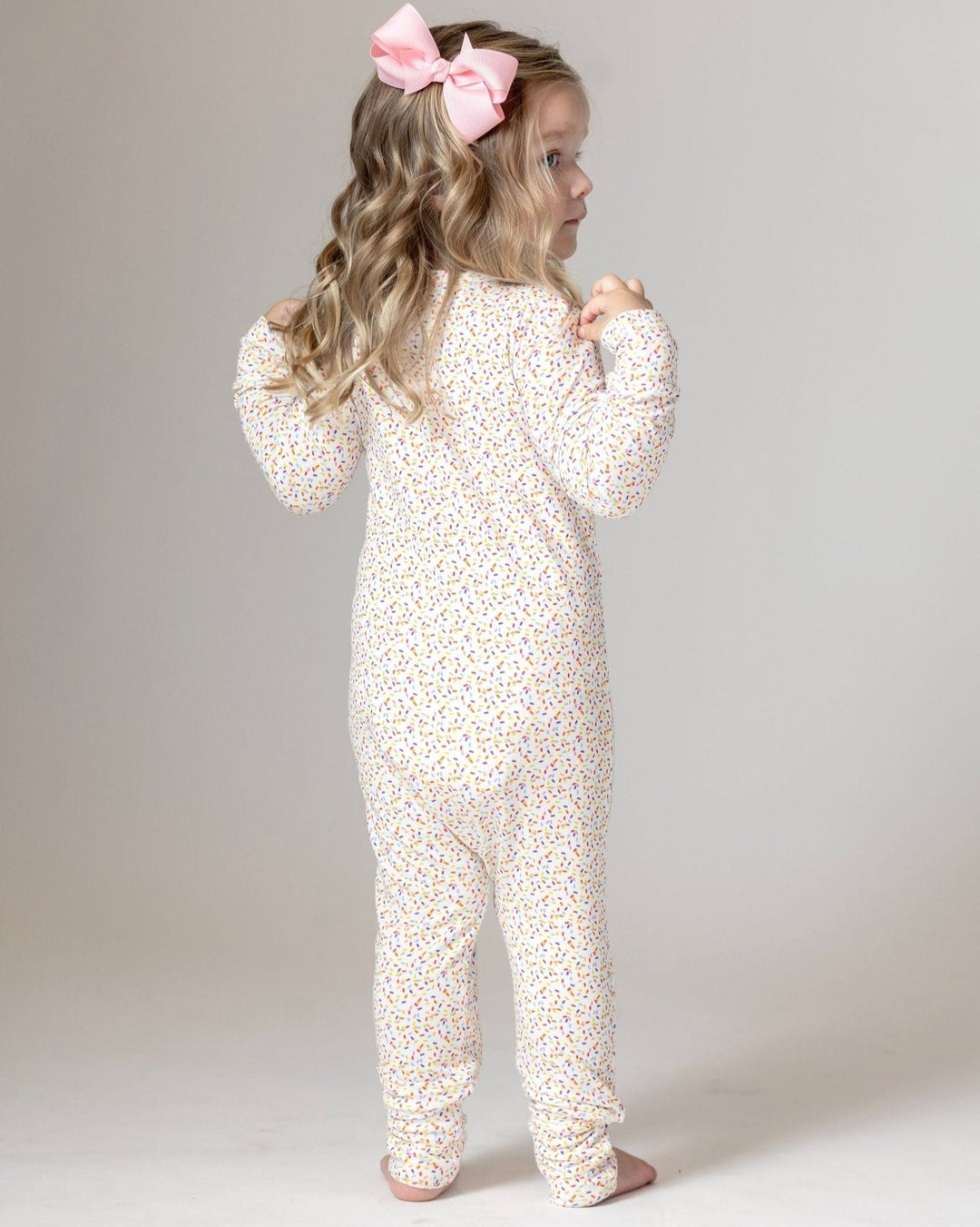 Bamboo romper pajamas, multicolor confetti dots, back view with pink bow
