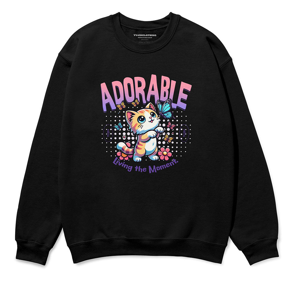 Black sweatshirt with cute cat graphic, butterflies, text “ADORABLE” and “Living the Moment”