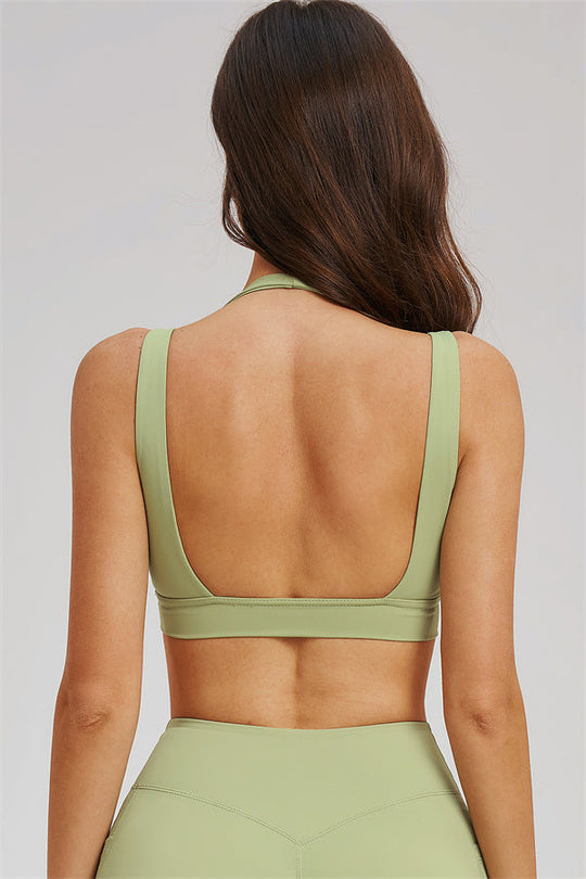Back view of olive green sports bra with scooped back, with flared leggings