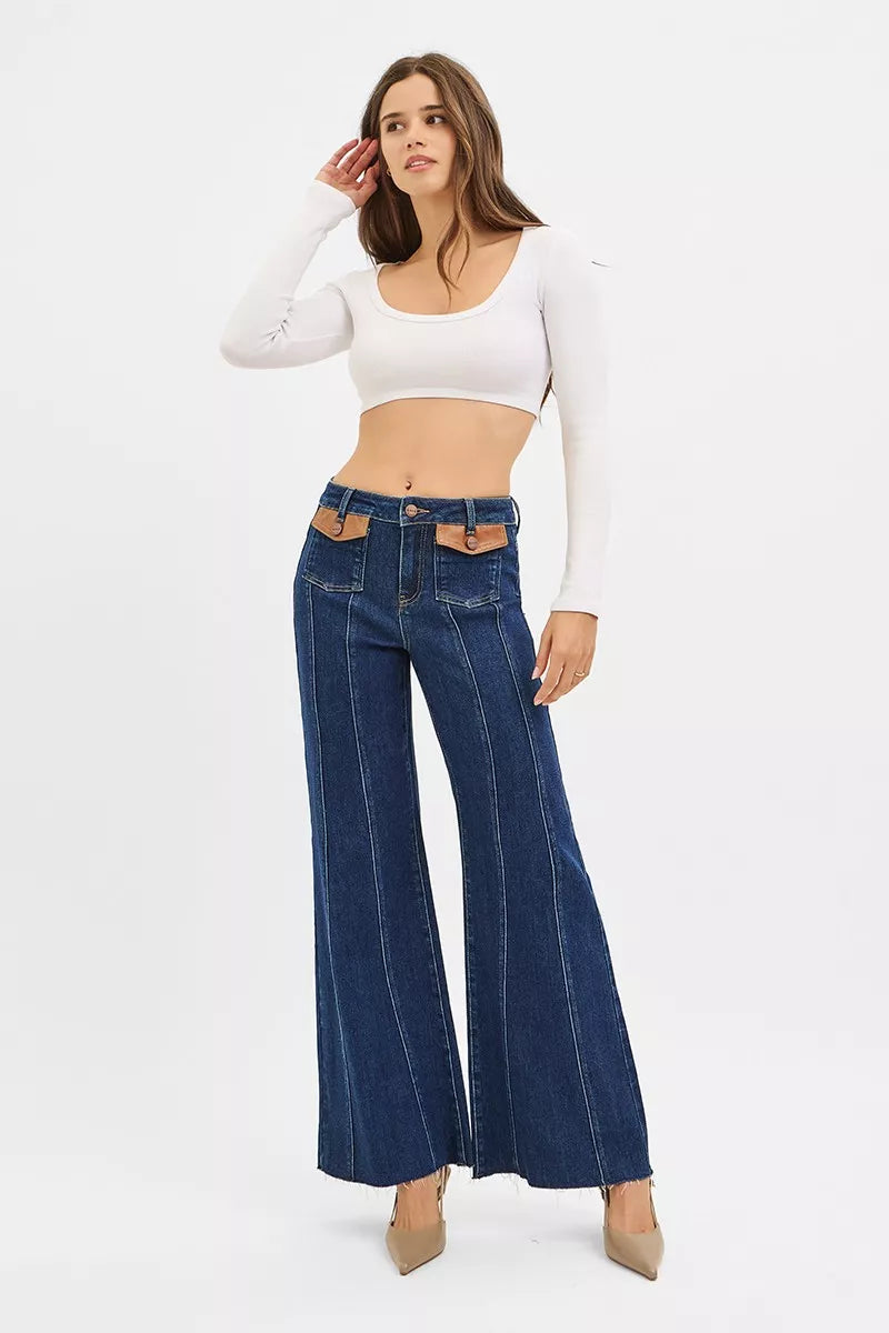 Model wearing dark high-rise wide-flare jeans with leather-look pocket tabs