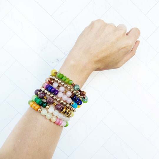 Perlenarmband am Handgelenk, mehrreihig mit grünen und violetten Perlen sowie Golddetails