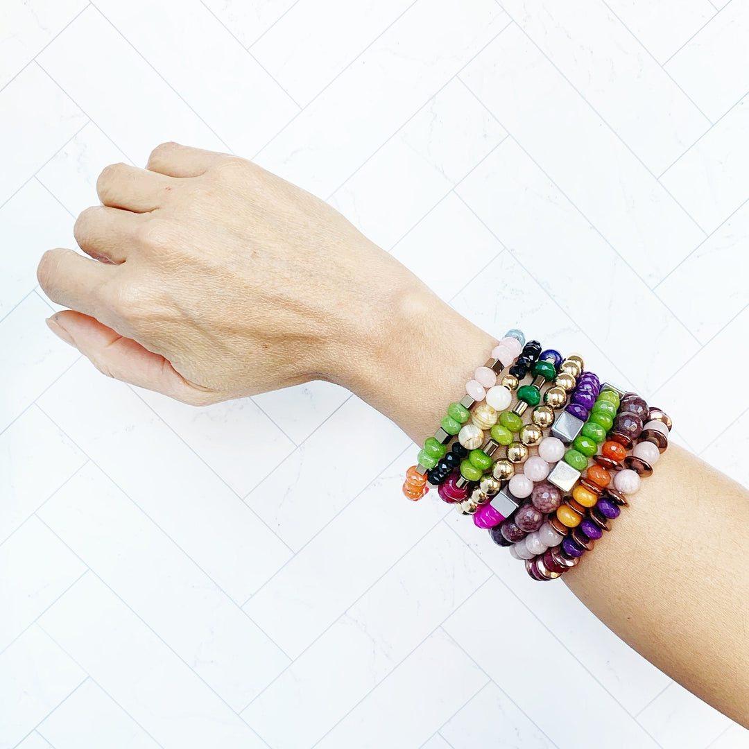 Perlenarmband am Handgelenk: pinke, grüne und lila Perlen mit kleinen Metallwürfeln