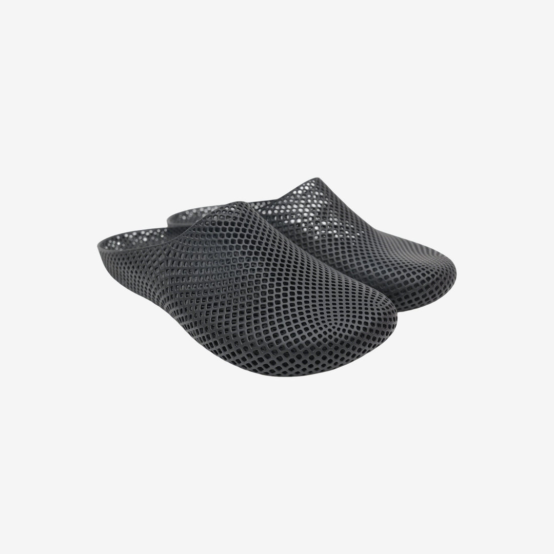 Black 3D printed slippers with openwork grid texture, slip-on clog style.