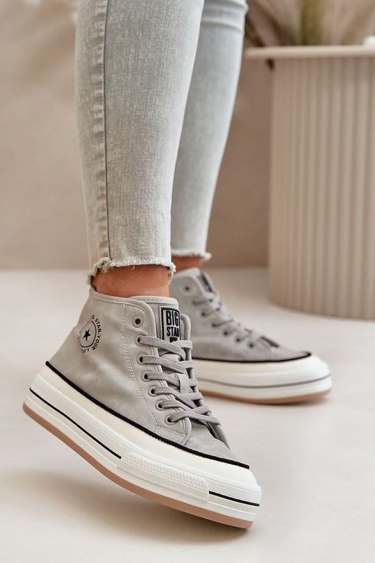 Light gray suede high-top sneakers on feet with jeans, lace-up front