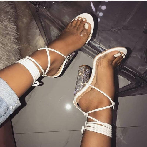 White strappy open-toe heels with ankle-wrap straps and jeweled block heel