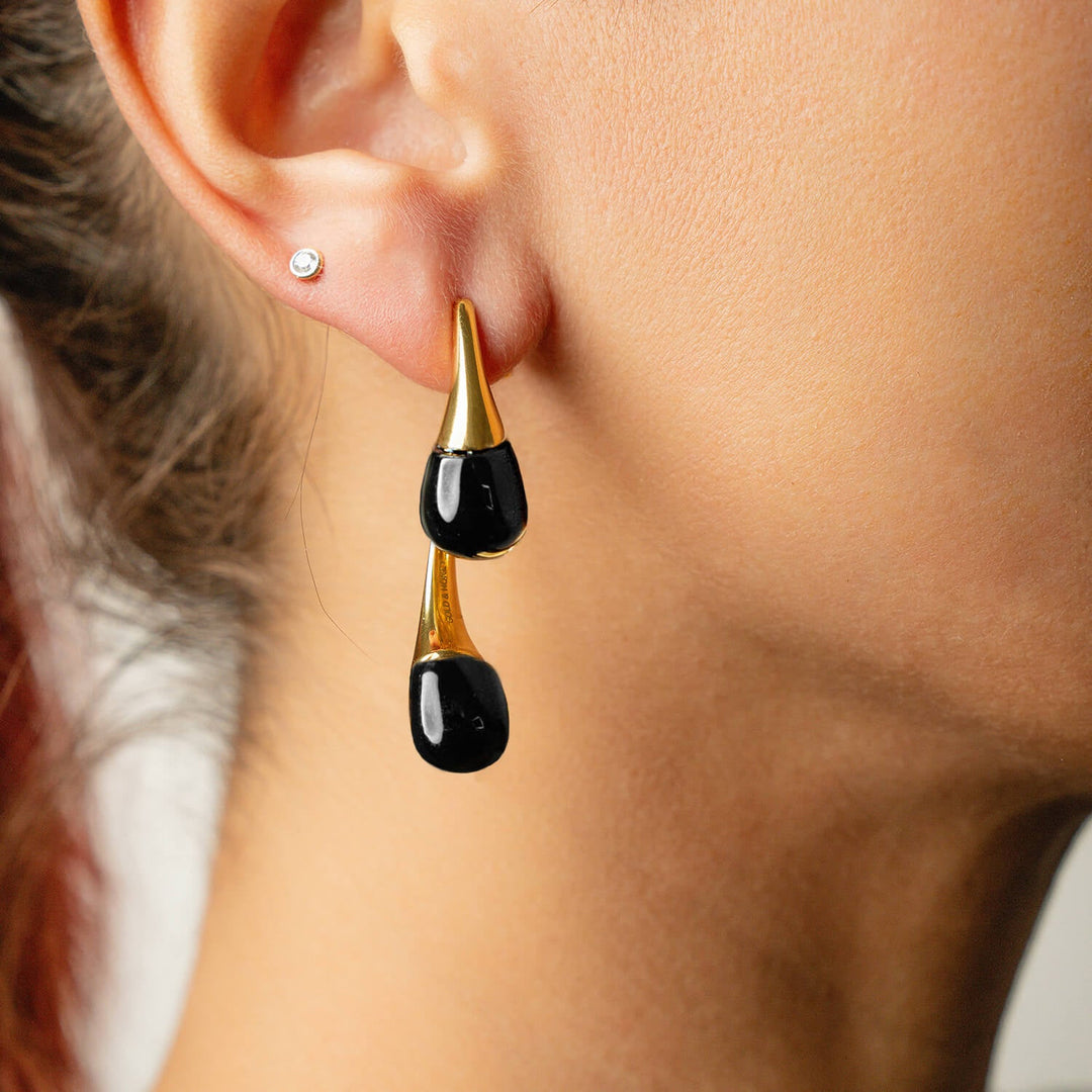 Black double drop earrings shown from side; gold-tone caps and shiny black drops.