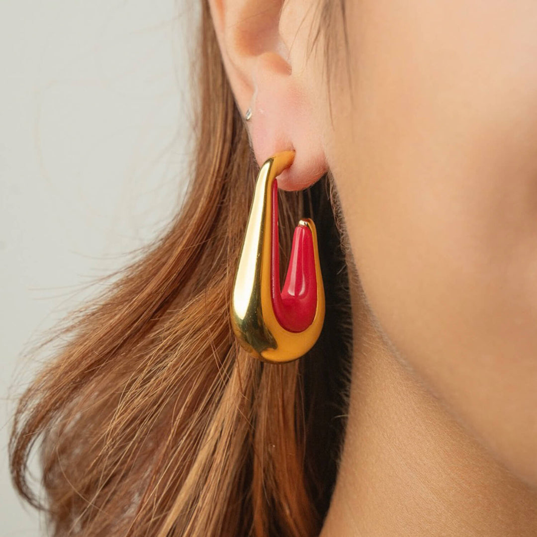 Pink flamingo drop hoop earrings on ear with gold-tone outer and pink enamel inner