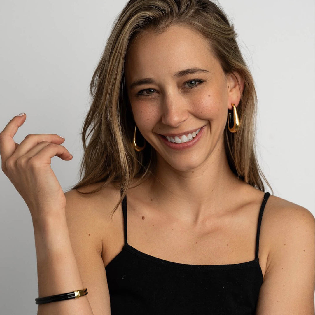 Drop hoop earrings with gold-tone hoops and dark black enamel inner on ear