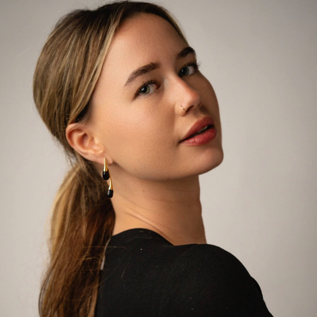 Black double drop earrings with glossy black drops and gold-tone caps on ear.
