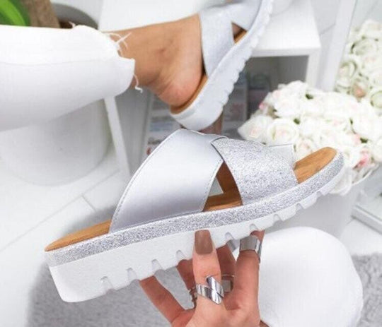 Silver women’s slide sandals with open toe, cross straps, and textured platform sole