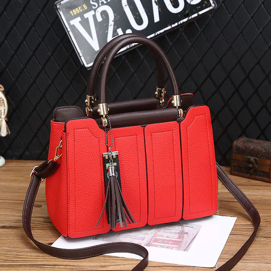 Red fashion shoulder tote with brown top handles, tassel charm, vertical panel front, gold accents