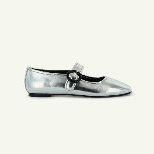 Silver flat Mary Jane shoe with round buckle strap and black sole trim