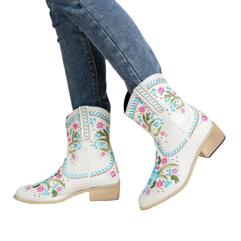 White embroidered mid-tube boots with colorful flowers, blue top trim, and wood-look heel
