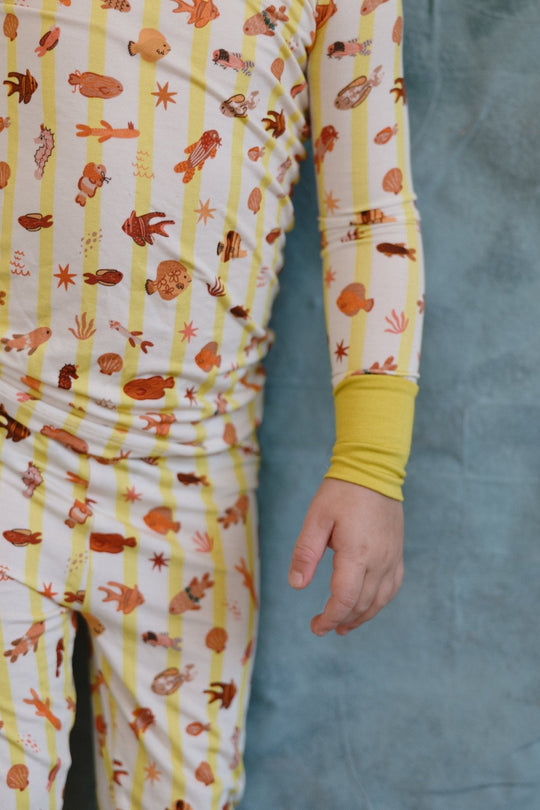 Close-up of Fancy Fins pajama sleeves and pants with critter print and yellow cuff detail