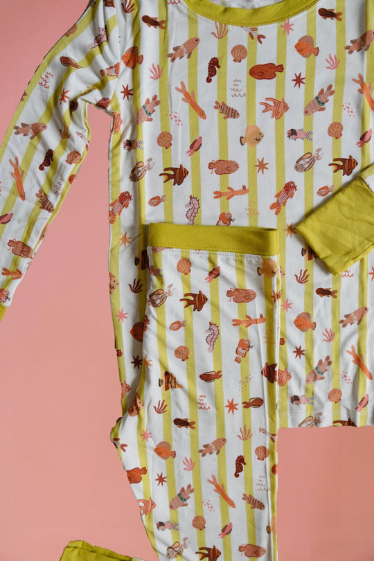 Fancy Fins pajama top and pants laid flat, vertical critter stripes with yellow neckline trim