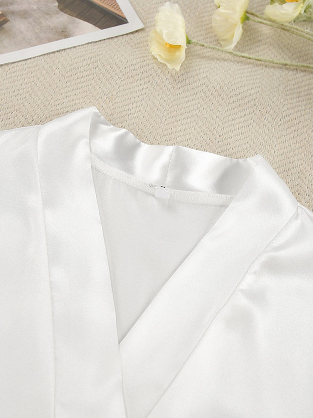 White cardigan fabric close-up with curved neckline seam and draped front panels