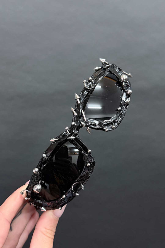 Holy Sunglasses close-up: oval black lenses with chrome spiked frame details