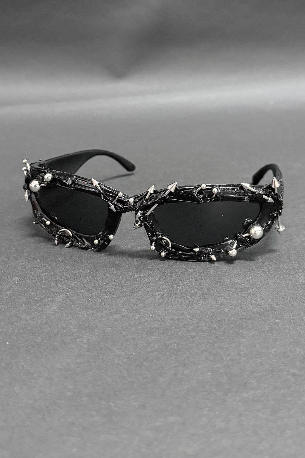 Black spiked sunglasses with oval lenses and chrome studded chain accents