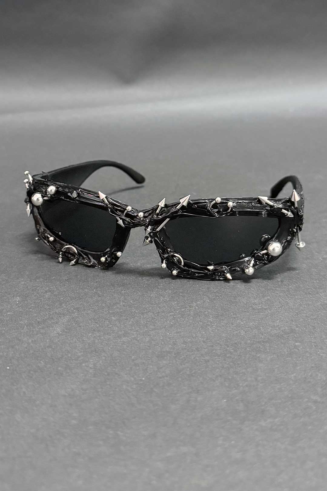 Black spiked sunglasses with oval lenses and chrome studded chain accents