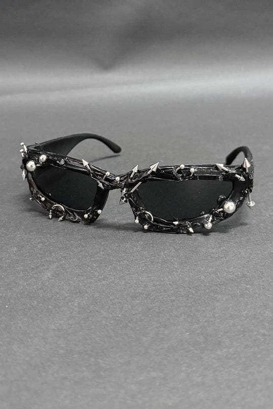Black spiked sunglasses with oval lenses and chrome studded chain accents