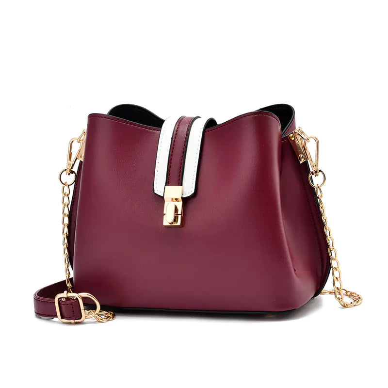 Burgundy bucket bag with white strap detail, gold hardware, and chain crossbody strap
