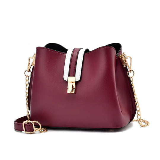 Burgundy bucket bag with white strap detail, gold hardware, and chain crossbody strap