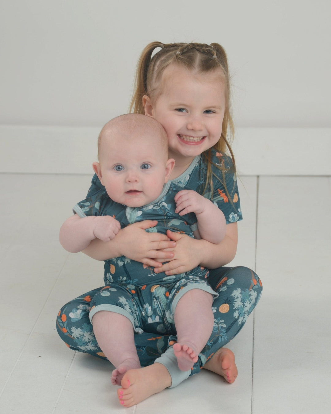 Jungle pajama set: teal printed short-sleeve pajama outfit on two children.