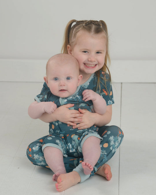 Jungle pajama set: teal printed short-sleeve pajama outfit on two children.