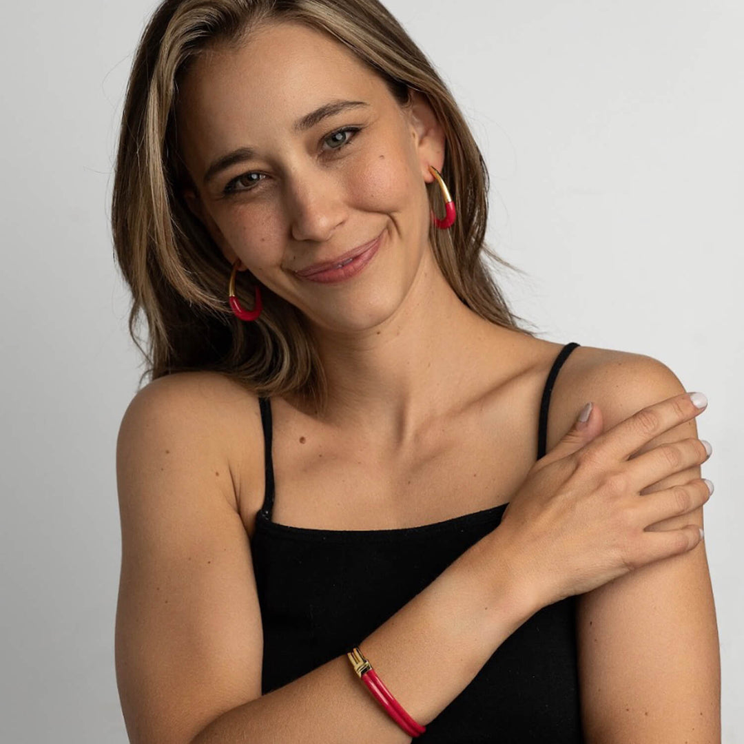 J Hoop earrings in Pink mit goldenen Enden, sichtbar am Ohr
