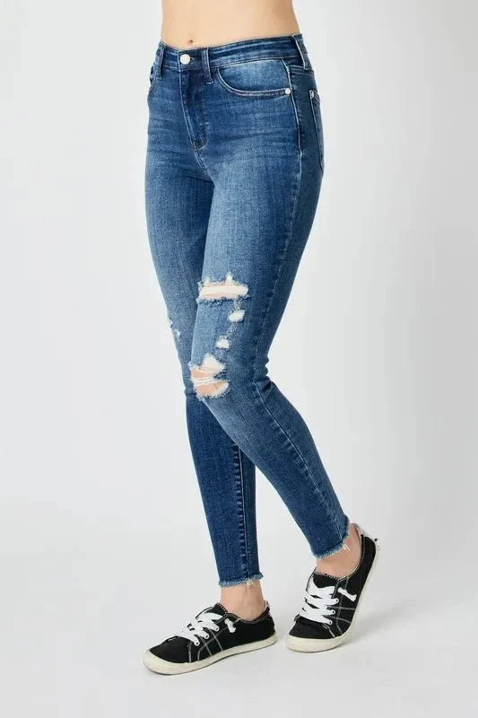 Dark high-waist skinny jeans, side view with ripped thigh detail